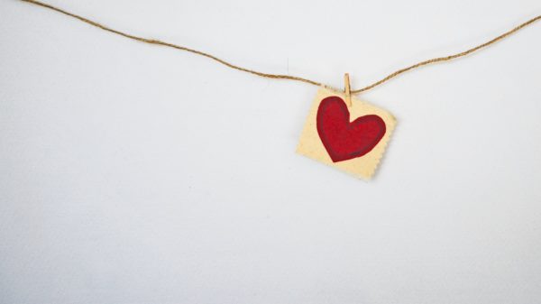 Paper, red heart hanging on a string with white background