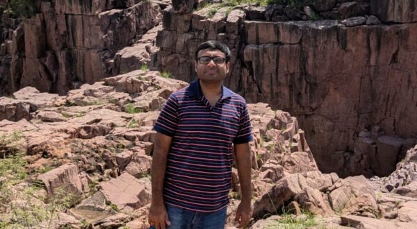 Featured contributor Mayank Bansal standing in front of a rock formation, looking to the camera.