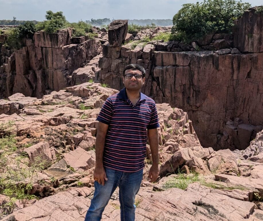 Featured contributor Mayank Bansal standing in front of a rock formation, looking to the camera.