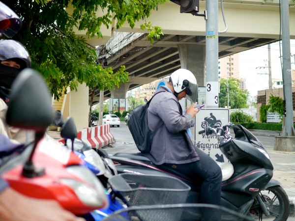 A man in Bangkok using his mobile device in traffic. 