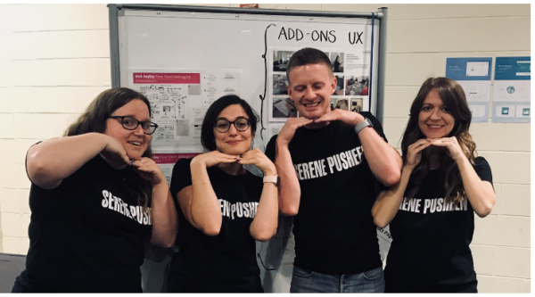 Photo of the four team members, standing in a row. All four wear black t-shirts that read, "Serene Pusheen." They are smiling and have their hands under their chins.