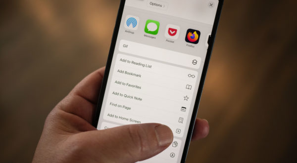 An iPhone in hand with the thumb near the Add to Home Screen item in the share menu.