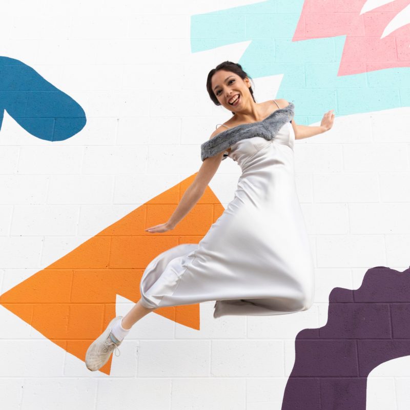 Xyla Foxlin jumps in front of a mural.