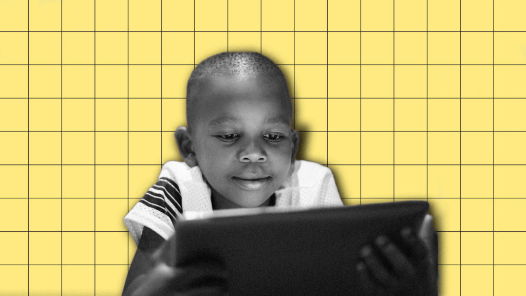 A child smiles while using a table computer.