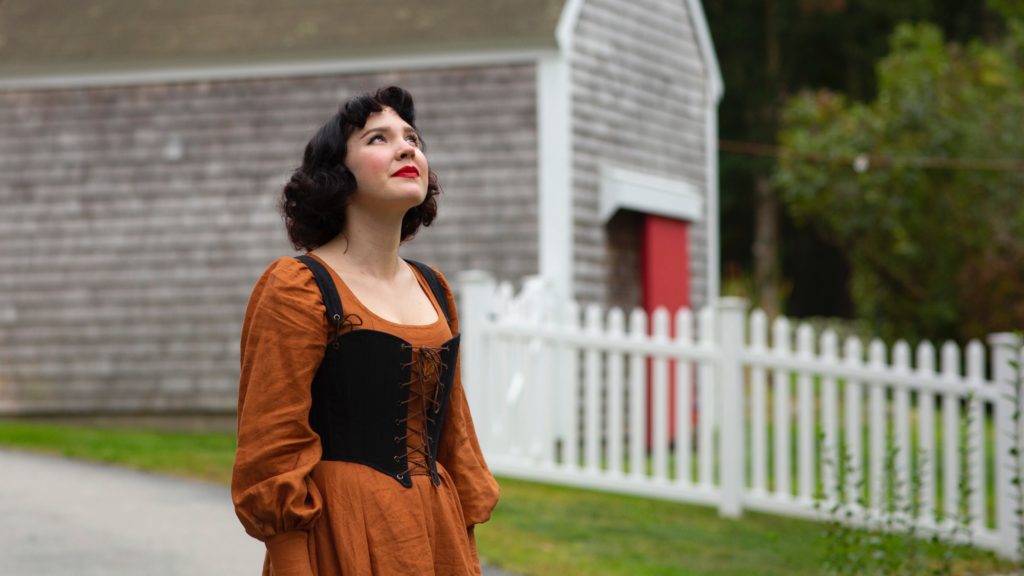 Rachel Maksy looks up while standing in front of a house.