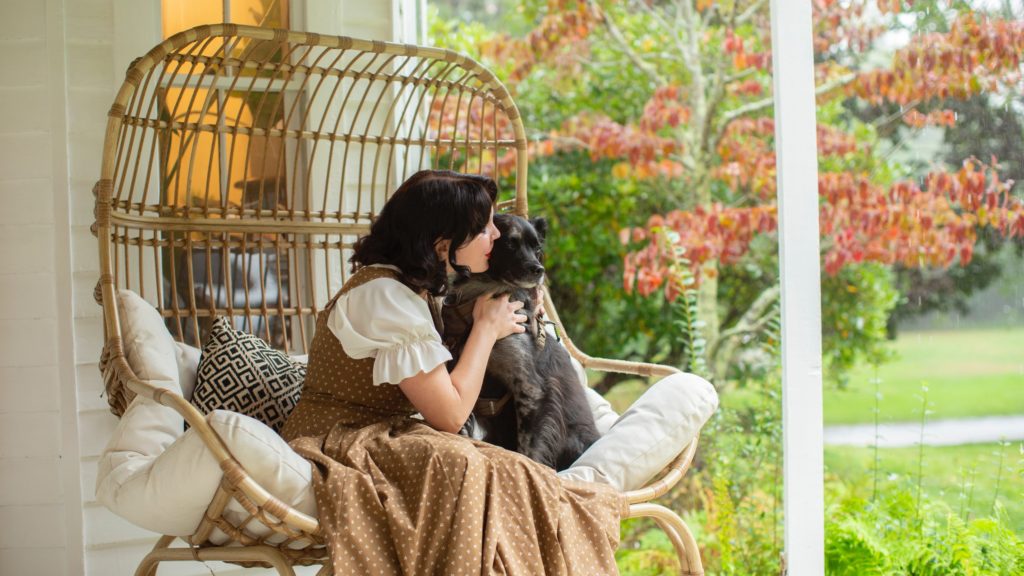Rachel Maksy holds her dog while sitting.