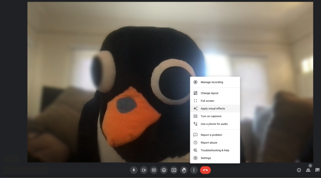 A screenshot of a Google Meet call, with a penguin selecting “Apply Visual Effects.”