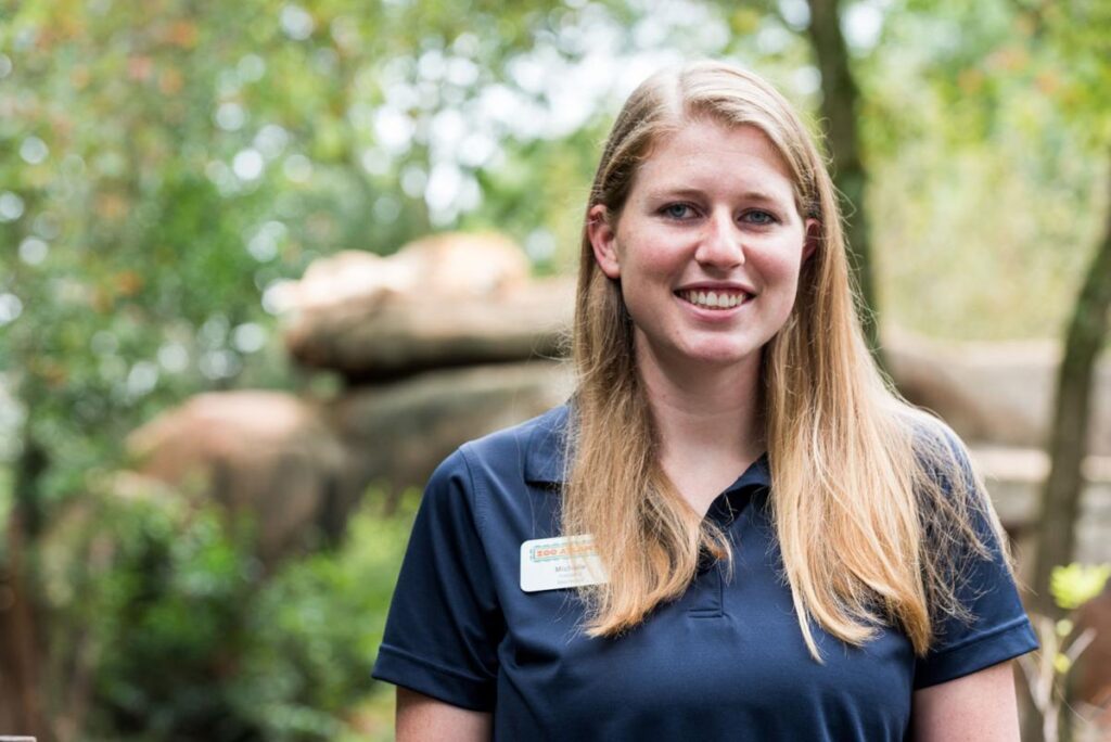 A zookeeper smiles at the camera.