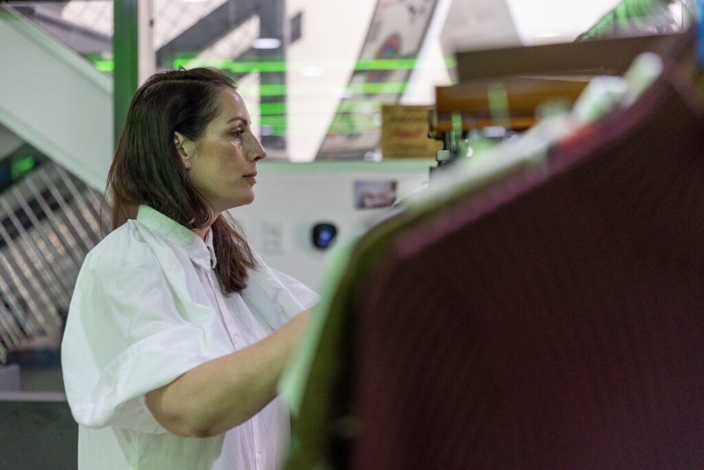 A woman wearing a white shirt focuses on organizing clothes in the boutique.