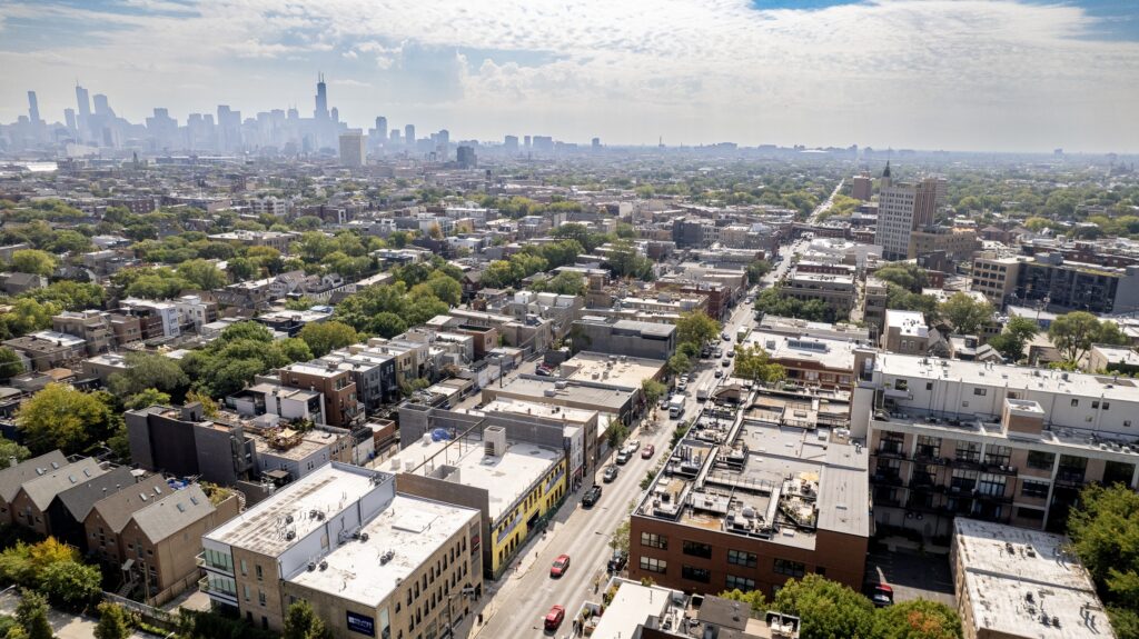 Aerial photo of Chicago’s Wicker Park neighborhood, with tree-lined streets, buildings, and the city skyline visible in the background.