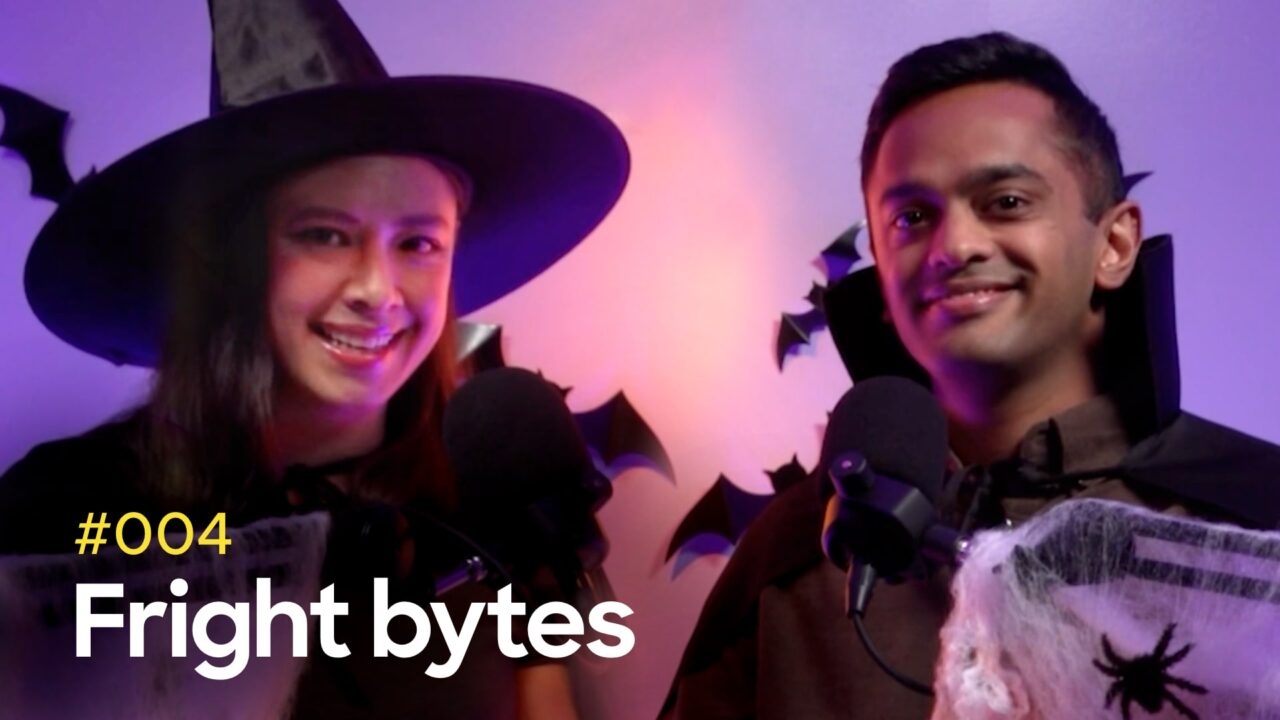 Two people dressed in Halloween costumes, one wearing a witch hat and the other a vampire cape, sit in front of microphones with bat decorations in the background. The text reads "#004 Fright bytes."